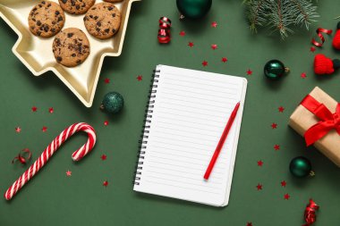 Yeşil arka planda Noel dekorlu ve kurabiyeli defter