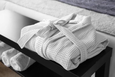 Şık bir otel odasında, yatağın yanında katlanmış bornozla ve havlularla komodinin yanında. Yakın plan.