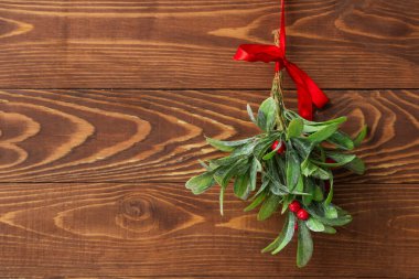 Ökseotu dalı, ahşap arka planda kırmızı yay, yakın plan.