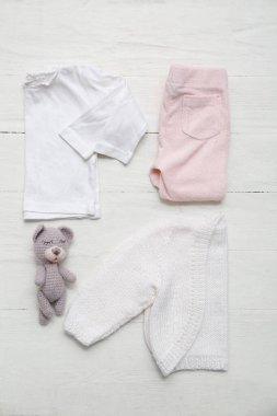 Süslü çocuk süveteri, pantolonu, beyaz tahta arka planda tişörtü ve oyuncağı.