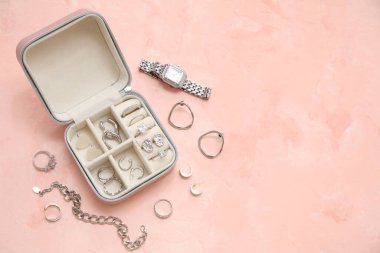 Pembe grunge arka planında farklı gümüş mücevherler ve kol saatine sahip açık organizatör