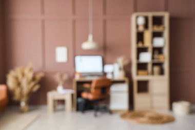 Çalışma yeri, raf ünitesi ve kahverengi duvarın yakınındaki otların olduğu modern ofis görüşü bulanık