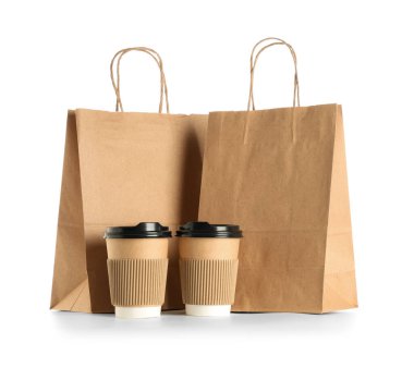 Beyaz arka planda kahve fincanları olan kağıt poşetler.