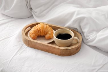 Bir fincan kahve ve beyaz çarşaflı kruvasan.