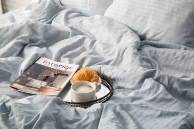 Bir fincan kruvasan, dergi ve gözlüklü kahve.