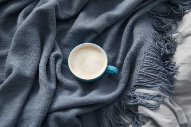 Yatağında battaniye olan bir fincan kahve.