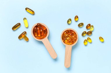 Mavi arka planda E vitamini kapsüllü tahta kaşıklar