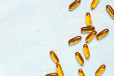 Açık mavi arkaplanda E vitamini kapsülleri