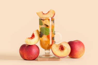 Bej arka planda şeftali ve yaban mersinli bir bardak lezzetli soğuk buzlu çay, yakın plan.