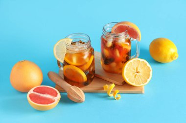 Bir bardak lezzetli soğuk buzlu çay ve mavi arka planda malzemeler.
