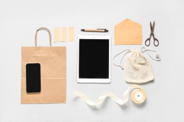 Tablet bilgisayarlı kompozisyon, cep telefonu ve gri arka planda teslimat kağıdı.