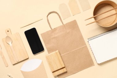 Bej arka planda cep telefonu, kase, yemek paketi ve teslimat kağıdı içeren kompozisyon