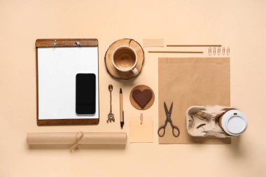 Bej arka planda cep telefonu, dosya, bir fincan kahve ve teslimat kağıdı içeren kompozisyon