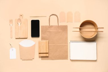 Bej arka planda cep telefonu, kase, yemek paketi ve teslimat kağıdı içeren kompozisyon