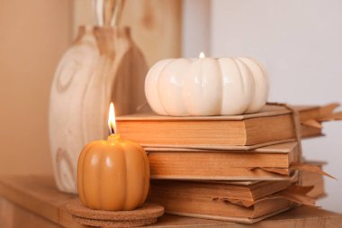 Oturma odasındaki masada kitap yığını ve yanan mumlar, yakın çekim.