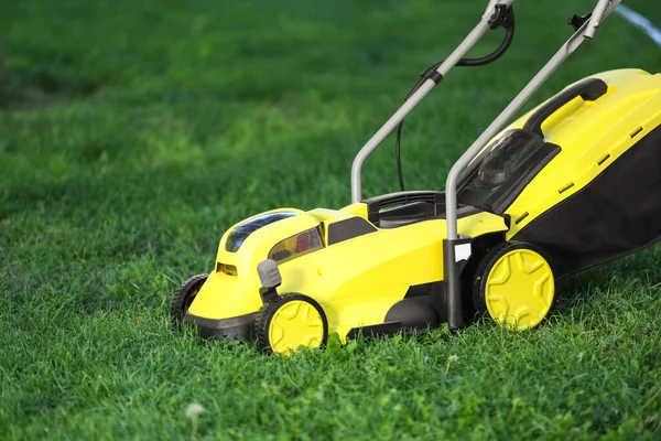 Yeşil çimlerin üzerinde modern çim biçme makinesi.