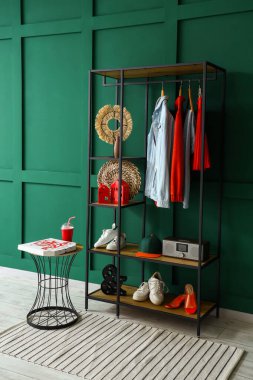 Salonun içinde raf ünitesi, giysi ve masa var.