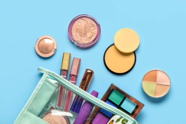 Mavi arka planda farklı dekoratif kozmetik ürünlere sahip çanta