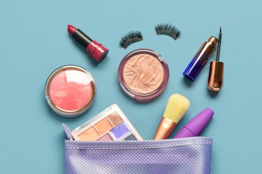 Mavi arka planda farklı dekoratif kozmetik ürünlere sahip çanta