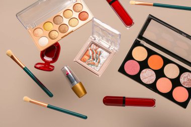 Bej arka planda uçan dekoratif kozmetik ürünleri