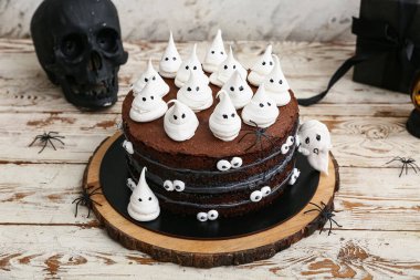 Tatlı Cadılar Bayramı pastası beyaz ahşap masada hayaletler, örümcekler ve kafataslarıyla süslenmiş.