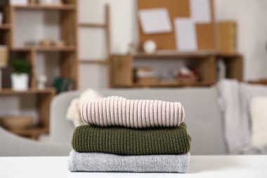 Oturma odasındaki masada şık bir kazak yığını.