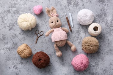 İplik, kanca ve makasla örülmüş tavşan oyuncağı gri grunge arka planda
