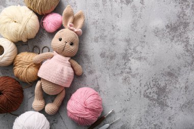 İplik, kanca ve makasla örülmüş tavşan oyuncağı gri grunge arka planda