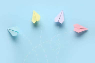 Mavi zemin üzerinde noktalı çizgiler olan renkli kağıt uçaklar