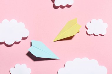 Pembe arka planda bulutlu kağıt uçaklar