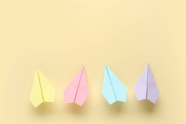 Açık sarı arkaplanda renkli kağıt uçaklar