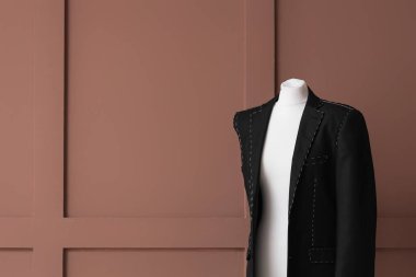 Kahverengi ahşap arka planda yarı bitmiş ceketli terzi mankeni.