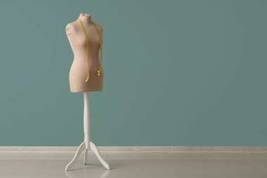 Turkuaz duvarın yanında mezurası olan terzi için manken.