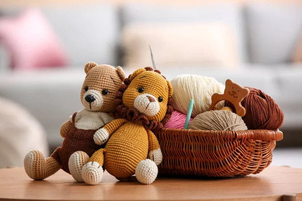 İplikli sepet, tığ işi kanca ve evdeki kahve masasında örülmüş oyuncaklar.
