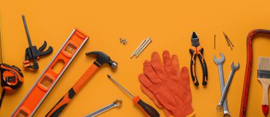 Turuncu arkaplanda eldivenler ve inşaat araçları
