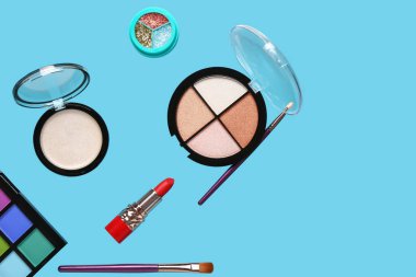 Mavi arka planda uçan dekoratif kozmetik ürünleri