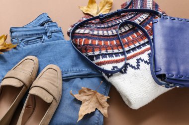 Renkli arka planda şık kadın kıyafetleri, el çantası, ayakkabı ve düşmüş yaprakları olan kompozisyon, yakın plan