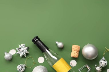 Bir şişe mantarlı şampanya ve yeşil arka planda Noel topları.