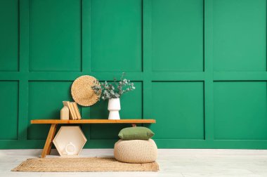 Taze okaliptüs dalları olan vazo ve oturma odasındaki bankta duran kitaplar.