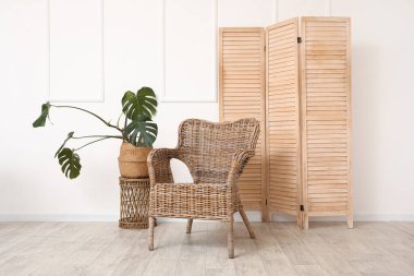 Hasır koltuk ve ev bitkisi odada katlanan perdenin yanında.