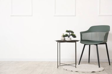 Beyaz duvarın yanındaki modern sandalye ve siyah masa.