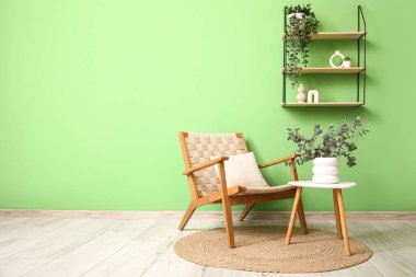 Okaliptüs dalları olan şık bir koltuk ve vazo. Odadaki yeşil duvarın yanındaki masada.