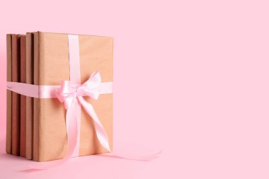 Pembe arka planda kurdeleyle bağlanmış kitap yığını