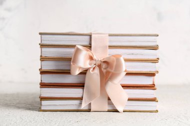Beyaz arkaplanda hediye kurdelesiyle bağlanmış kitap yığını