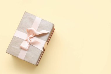 Sarı arka planda hediye kurdelesiyle bağlanmış bir yığın kitap.