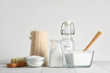 Kabartma tozu, kaşık ve temizlik malzemeleriyle sirke şişesi beyaz arka planda.