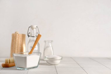 Kabartma tozu, kaşık ve temizlik malzemeleriyle sirke şişesi beyaz arka planda.