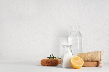 Bir şişe kabartma tozu, sirke, limon ve beyaz grunge arka planda temizlik malzemeleri.