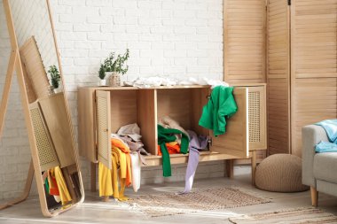 Dağınık elbiseli, aynalı ve beyaz tuğlalı duvarın yanında katlanan bir elbise.