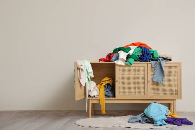 Giysileri dağınık, halıları beyaz duvarın yanında, oturma odasında.